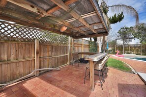 An outdoor patio with a wooden pergola, a table with chairs, and a pink flamingo float in the background. - Near the Mayo Clinic and 6 blocks from Ocean 3 bedrooms Pool Home (Jacksonville Beach)