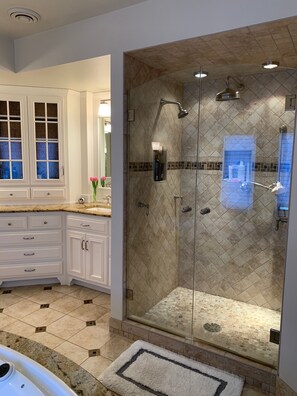 Une salle de bain moderne avec une douche à parois de verre, des meubles blancs et un sol carrelé.