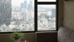 A modern living room with a large window, a grey sofa, a white coffee table, and a hanging pendant light.