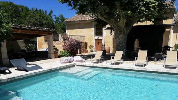 Una piscina nítida amb gandules i una pèrgola.