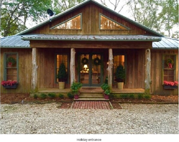 A wooden cabin with a porch, two windows, and a front door.