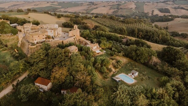 An aerial view of a castle-like structure surrounded by lush greenery and fields. - La casa in piazzetta in Borgo Loretello (Loretello)