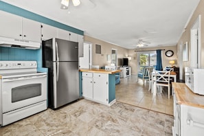 A modern kitchen with a stainless steel refrigerator, white cabinetry, and a wooden countertop.
