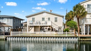 Una casa frente al agua con balcón, escaleras y muelle.