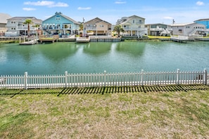 A waterfront property with multiple houses, a dock, and a white fence.