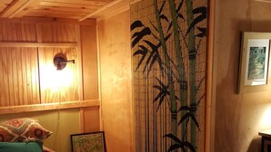 Un dormitorio con una cama grande, cabecera de madera, biombos de bambú y una mesita de noche con lámpara.