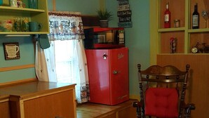 Una cocina acogedora con un refrigerador rojo, sillas de madera y una mesa de comedor.