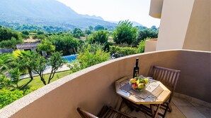 A balcony with a table set for two, a bottle, and a bowl of fruit. - Apartments Setemana (Zupa dubrovacka)