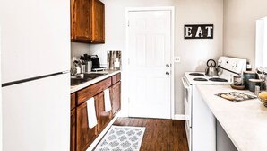 Une cuisine de taille réduite, avec des meubles en bois, un réfrigérateur blanc, une cuisinière et un panneau indiquant « MANGER ».