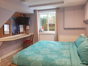 A bedroom with a bed, a TV on a shelf, a window with curtains, and a chair.