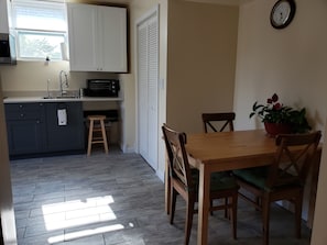 A kitchen with a sink, stove, and cabinets, a dining table with chairs, and a potted plant.