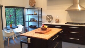 A modern kitchen with a wooden island, black cabinets, and a stainless steel range hood.
