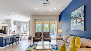 A spacious living area with a kitchen, dining area, and a large window with a view of greenery. - POOL HOME - Luxury Windsor Palms Resort - 6 miles to Disney! POOL HEAT INCLUDED! (Kissimmee)