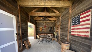 Een rustiek houten interieur met een eettafel en stoelen, een houten bank, een grote Amerikaanse vlag en een rustieke kroonluchter.