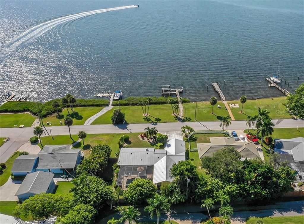 An aerial view of a coastal residential area with houses, a dock, and a boat.