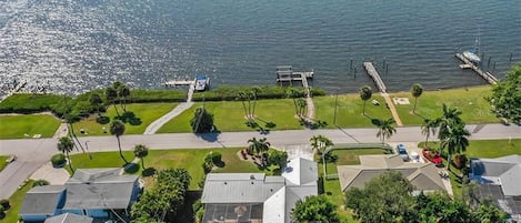 Vista aérea de uma área residencial costeira com casas, um cais e um barco.