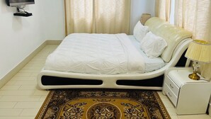 A neatly arranged bedroom with a bed, a bedside table, a lamp, and a television mounted on the wall.