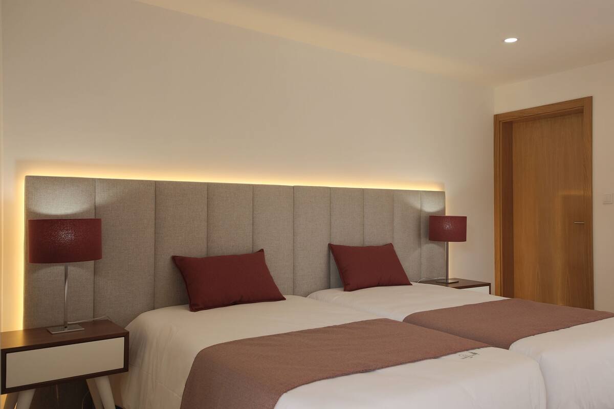 A hotel room with a large bed, two bedside tables, and a wooden door.