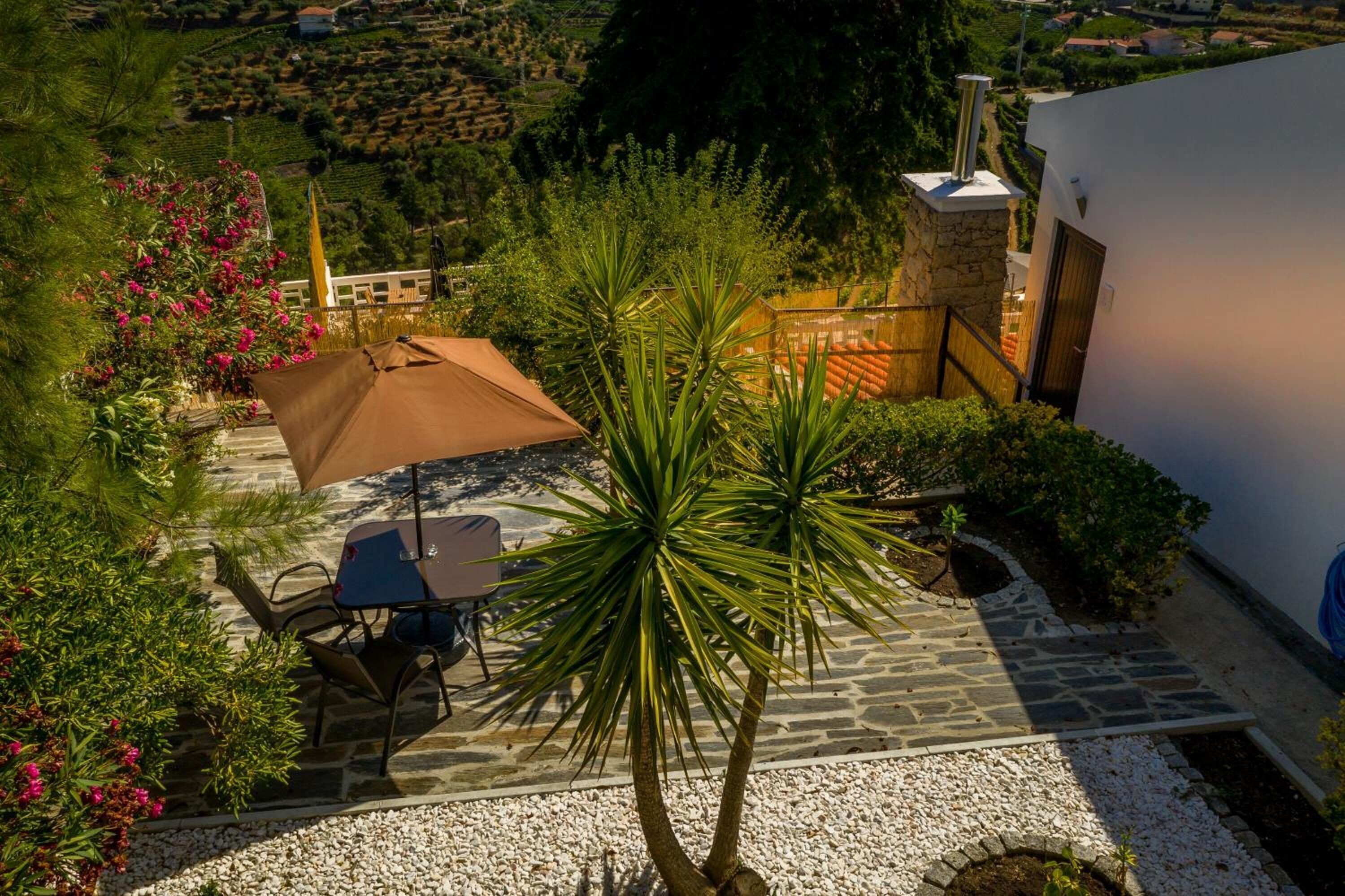 A patio with a table and chairs, surrounded by plants and a stone wall.