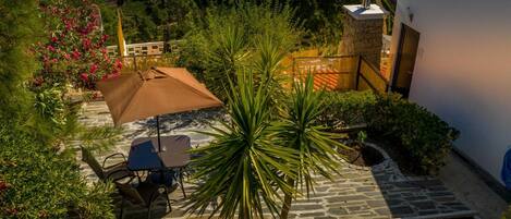 A patio with a table and chairs, surrounded by plants and a stone wall.