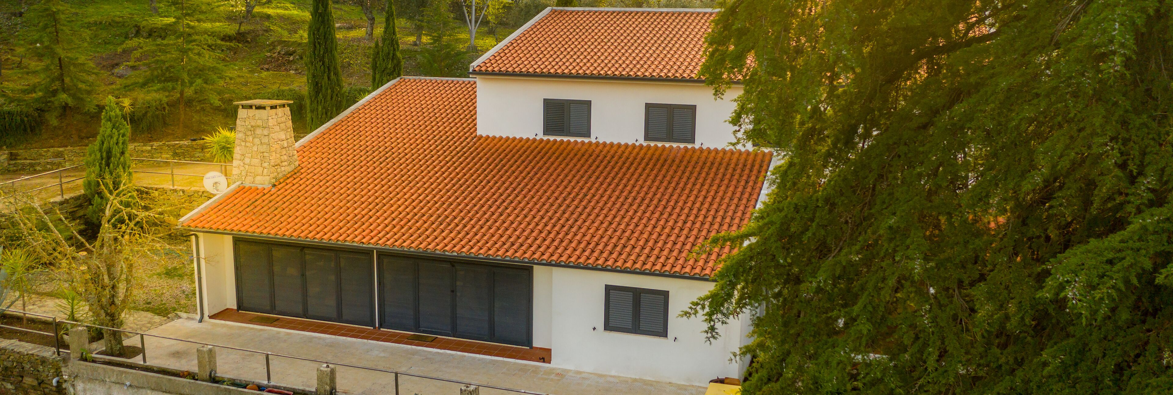 Una casa de dos pisos amb teulada de rajoles vermelles, grans portes corredisses i una xemeneia.