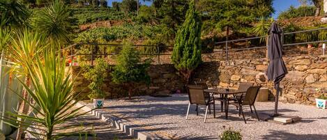 A patio area with stone flooring, outdoor furniture, and potted plants.