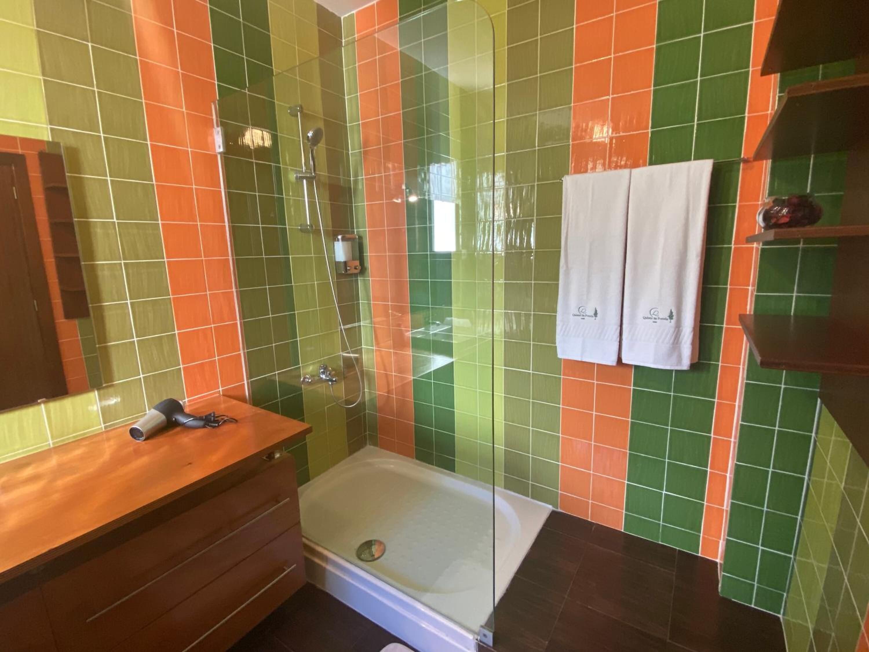 Un baño con ducha, tocador de madera y cabina de ducha con mampara de vidrio.