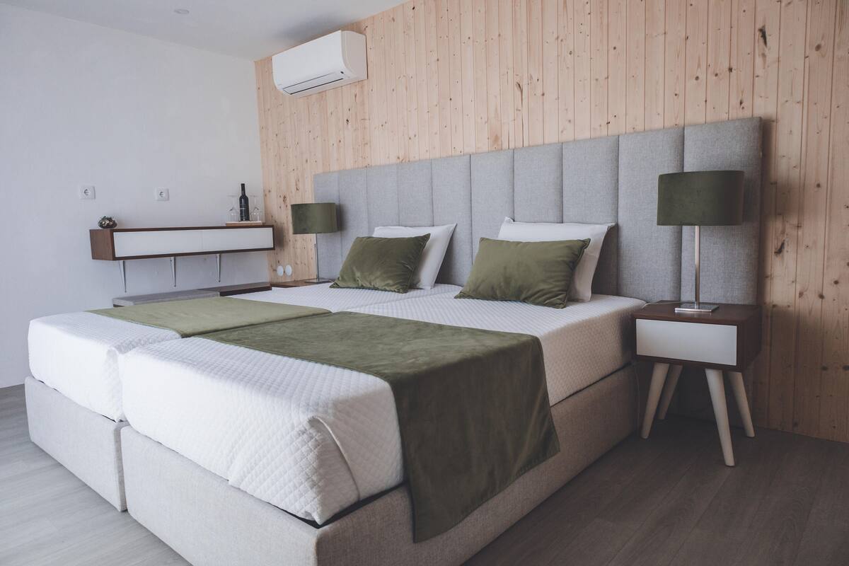 A modern bedroom with a large bed, two bedside tables, a nightstand, and a wall-mounted shelf.