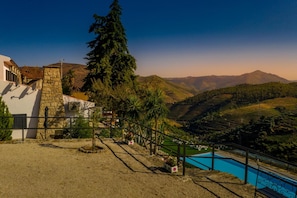 A hillside property with a pool, stone walls, and a view of the surrounding hills. - Quinta da Portela Douro (Armamar)