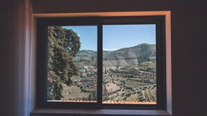 A window with a view of a hilly landscape, including trees and buildings. - Quinta da Portela Douro (Armamar)