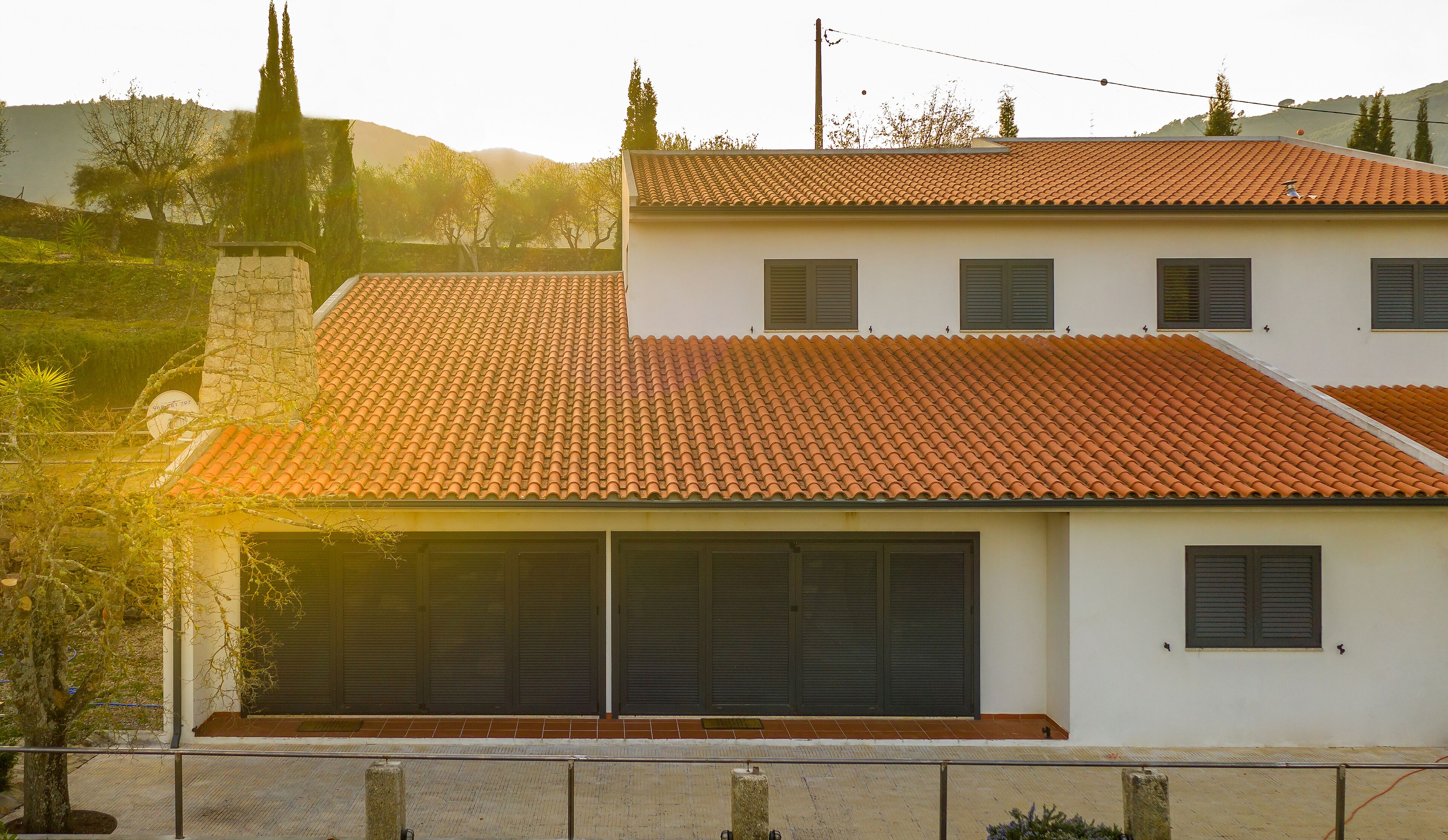 Uma casa de dois andares com telhado em telhas, persianas e uma garagem.