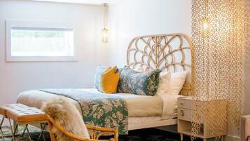 Un dormitorio con cama, una silla, una mesita de noche y una lámpara decorativa.