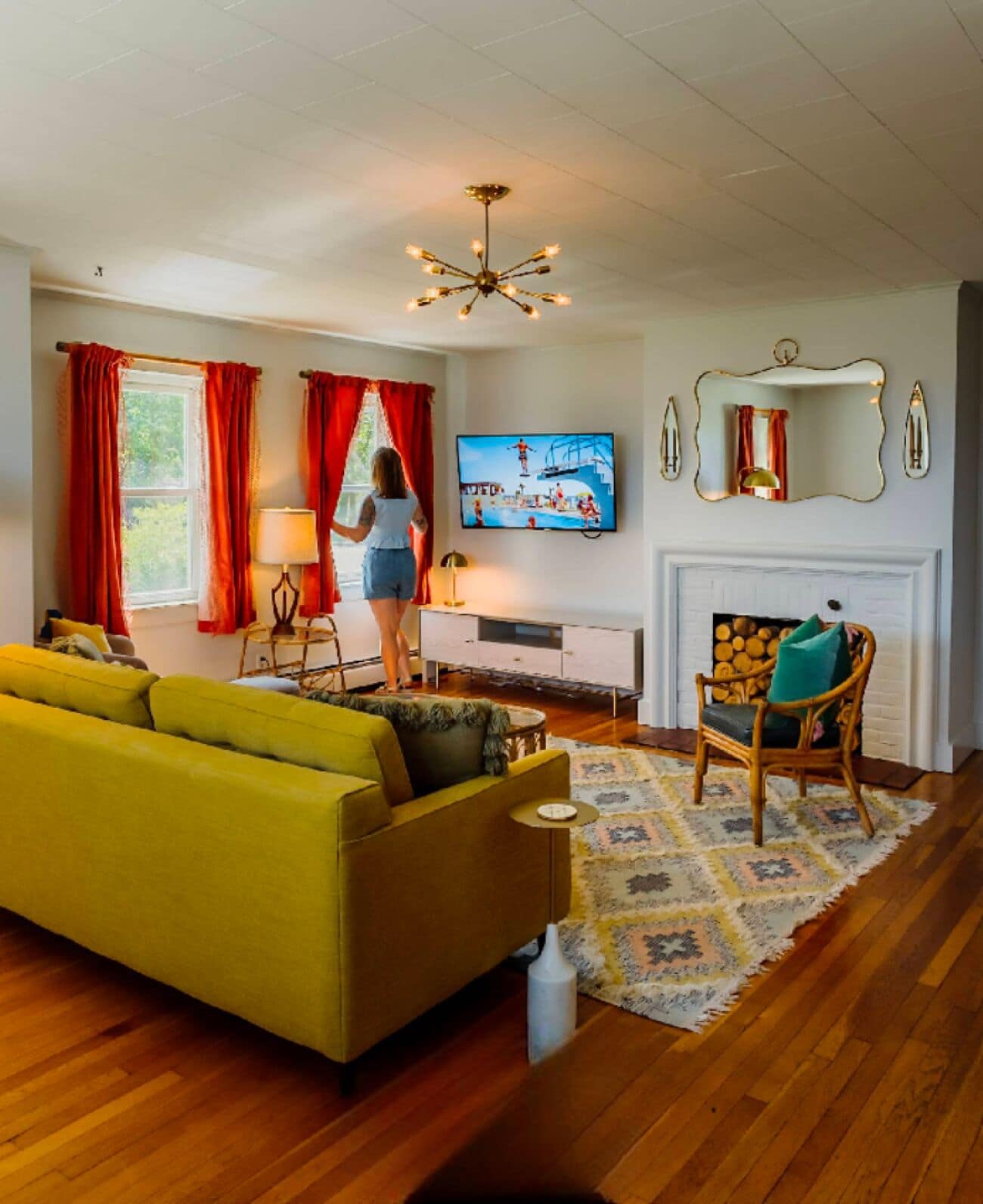 A living room with a yellow sofa, a wooden chair, a TV, and a fireplace.