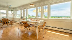 A spacious room with a large window, wooden flooring, and a dining table with chairs. - Rye Motor Inn - Oceanfront, Walk to Beach (Rye)