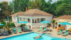A swimming pool with lounge chairs and umbrellas, surrounded by a building with a tiled roof. - Rye Motor Inn - Oceanfront, Walk to Beach (Rye)