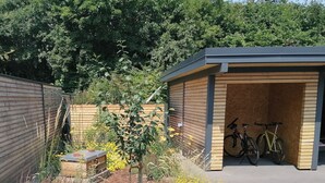 A covered bicycle parking area with a wooden structure and two bicycles inside. - Little house on the historic city wall (Höxter)