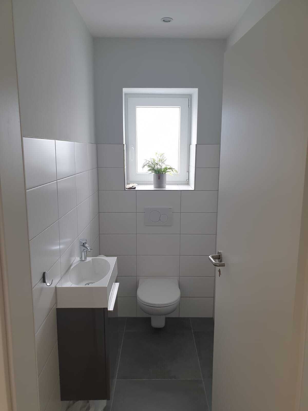 A compact bathroom with a window, a sink, and a toilet.