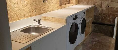 A compact kitchen with a sink, a washing machine, and a countertop.