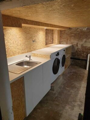 Una cocina compacta con un lavabo, lavadora y encimera.