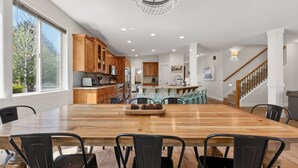 Une cuisine spacieuse avec des meubles en bois, une grande table à manger et un lustre.