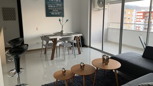 A modern living room with a dining area, a large sliding glass door to a balcony, and a motivational quote on the wall. - Executive apartment (Cali)