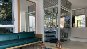 A modern reception area with a green sofa, a wooden reception desk, and glass doors leading outside. - Executive apartment (Cali)