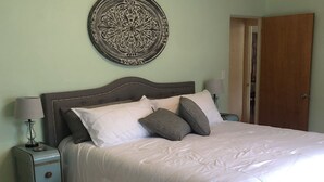 Ein Schlafzimmer mit Bett, Nachttischen, Wanddeko und einer Tür.