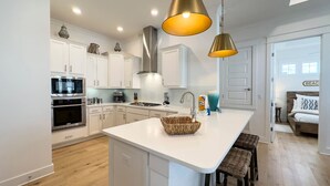 Una cocina moderna con armarios blancos, una isla central e iluminación colgante.