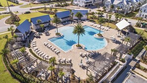 Vista aérea de un resort con una piscina central, varias zonas de descanso y jardines bien cuidados.