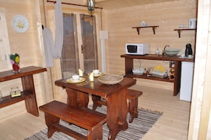 A wooden interior with a dining table, benches, a microwave, and a sink.