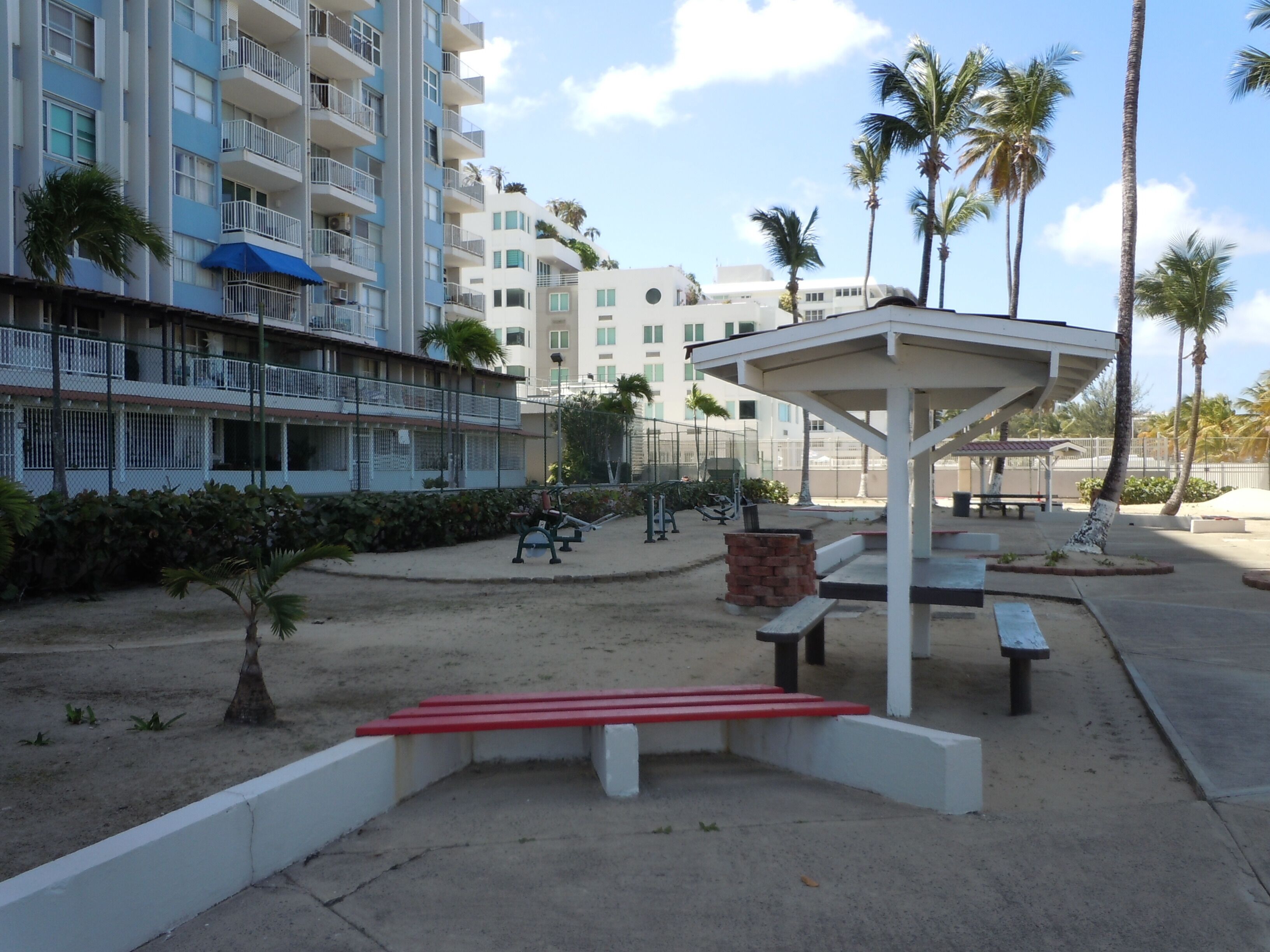 A resort area with a covered seating area, exercise equipment, and a building with balconies.
