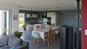 Een moderne keuken met een centraal eiland, een eethoek met een tafel en stoelen, en een ingebouwde kookplaat.