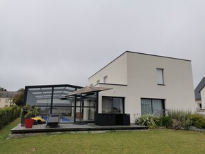 A modern two-story house with a glass conservatory, a deck with outdoor furniture, and a swimming pool. - Heated swimming pool, seaside, ocean view, walking distance to beach, Brittany (CLOHARS CARNOET)