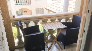 Ein Balkon mit zwei Korbstühlen und einem Holztisch.